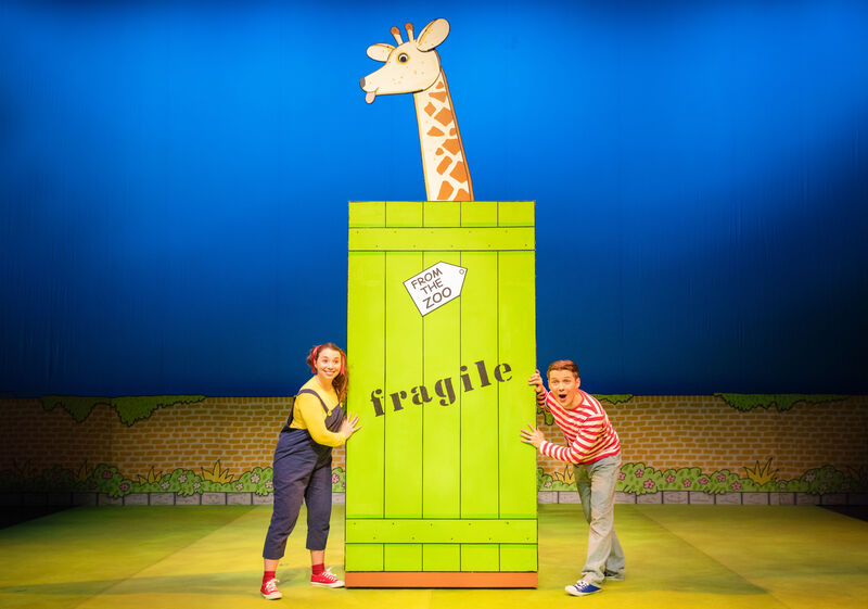 A Giraffe popping out of the top of a green box 