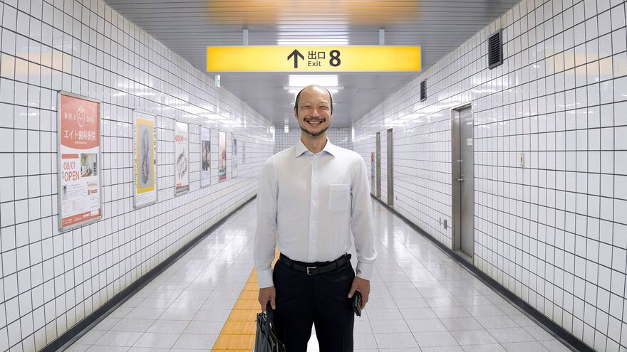 A man stood grinning under an Exit 8 signpost