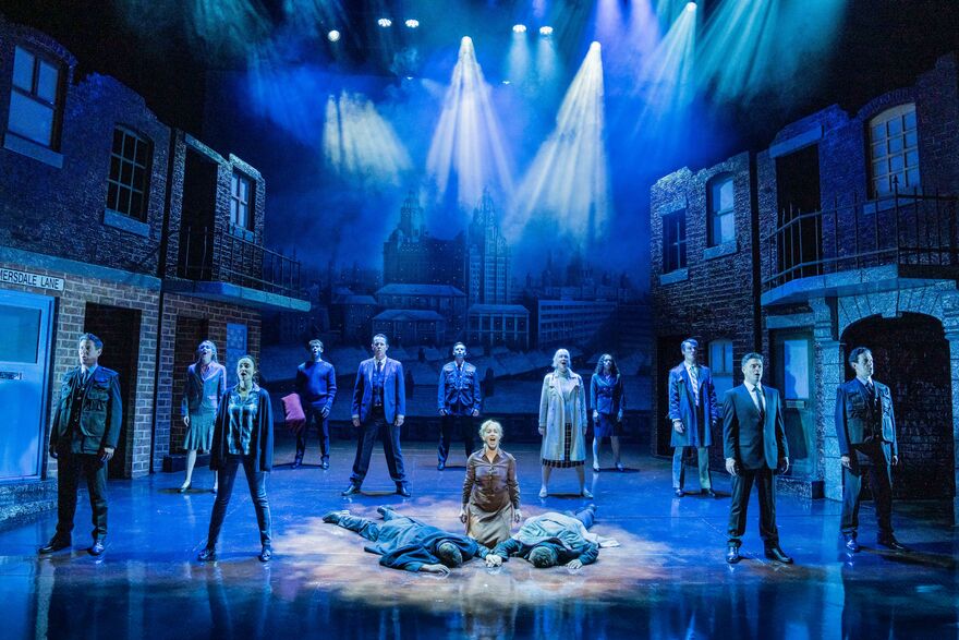 Blood Brothers Production Shot of cast on stage facing forward, two cast members are face down on the stage floor