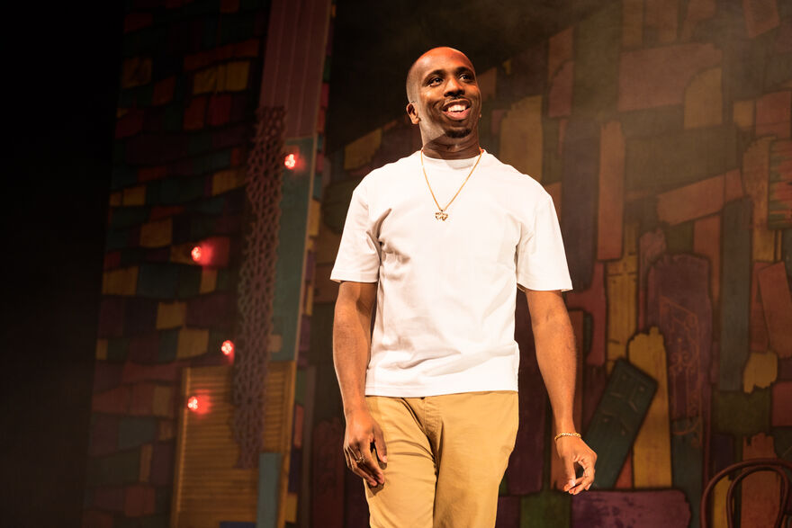 Kiell Smith Bynoe on stage in a white tshirt and beige chino trousers