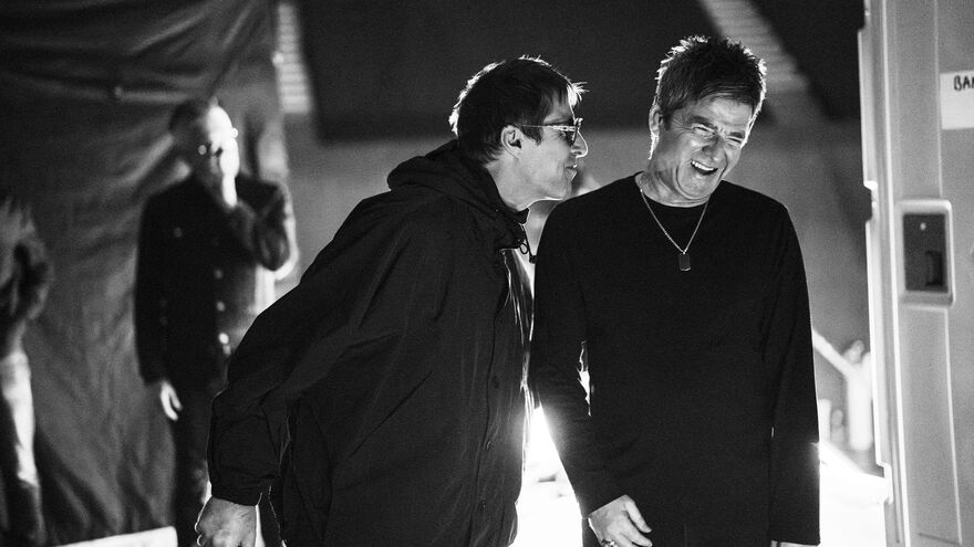A black and white photograph of Liam and Noel Gallagher behind the scenes at a shoot.