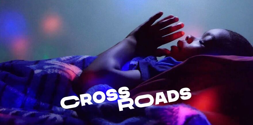 A young boy lays in a blanket with his eyes closed and his hands in prayer