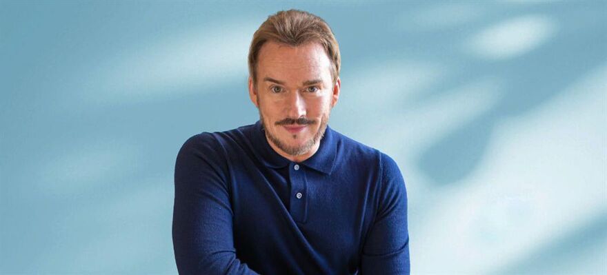 Russell Watson crouching down in a dark blue shirt