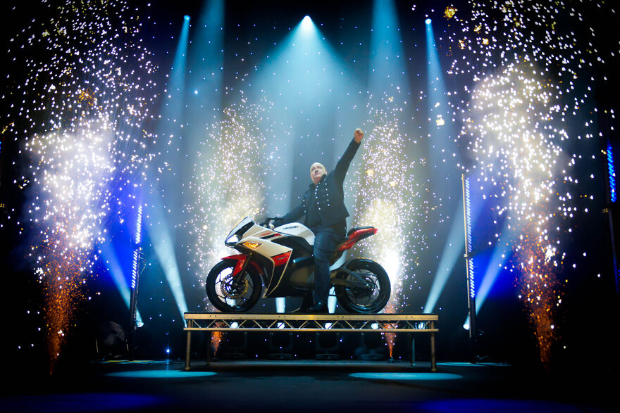 A man on a motorbike on stage with sparks