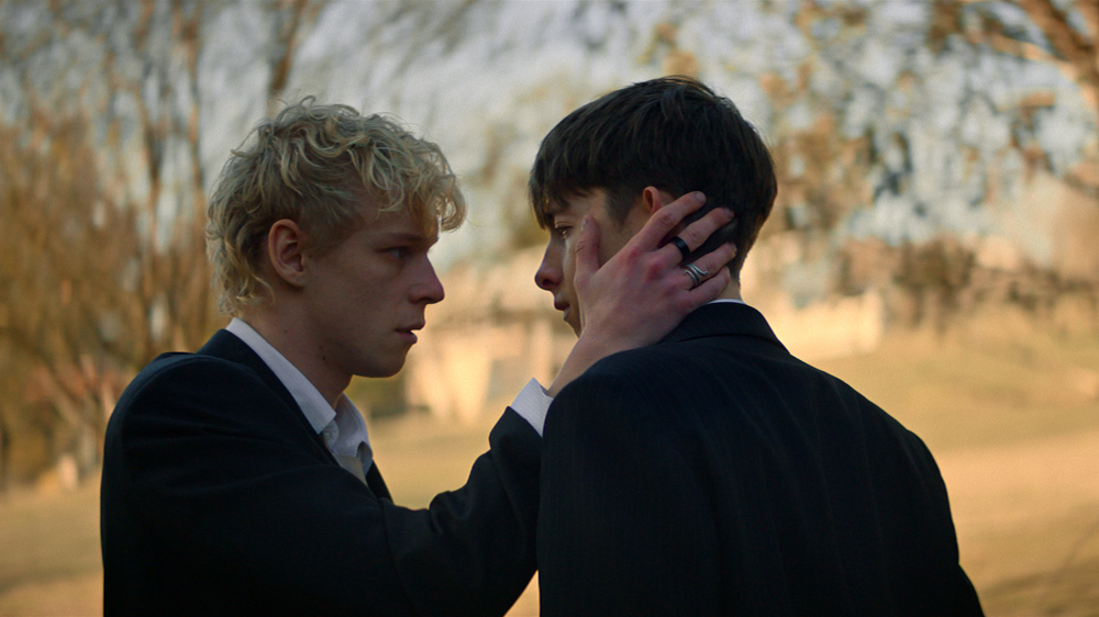 Two male actors face eachother, one with a hand on the others face