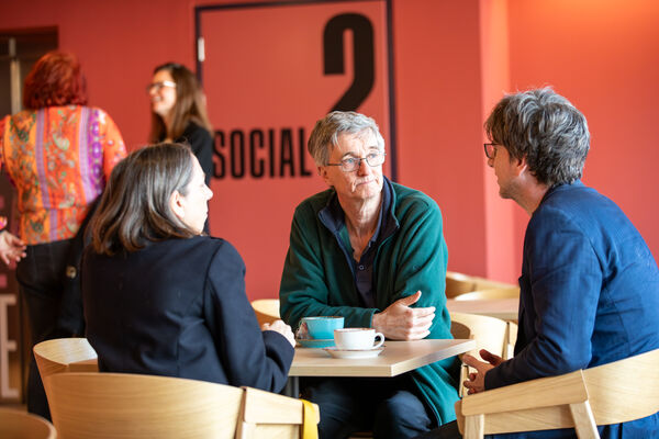 Group of three people sat at table in cafe