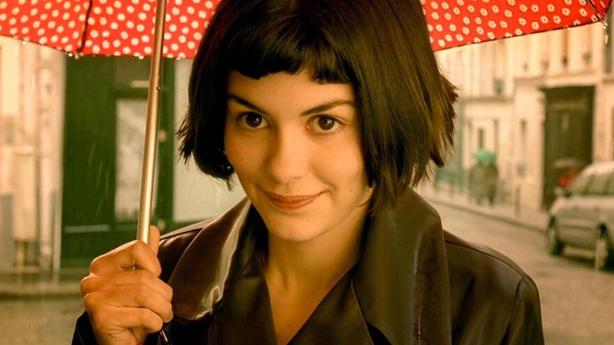 Amélie standing in the rain with an umbrella