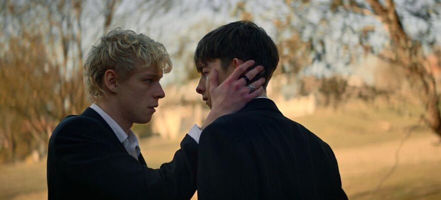 Two male actors face eachother, one with a hand on the others face