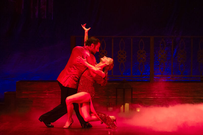 A man and a woman dance the tango under a red light