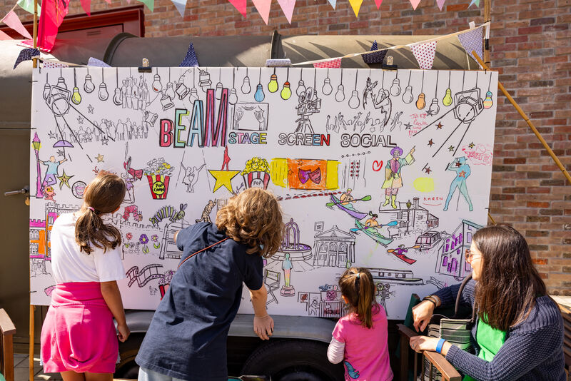 A group of children colour in a large mural