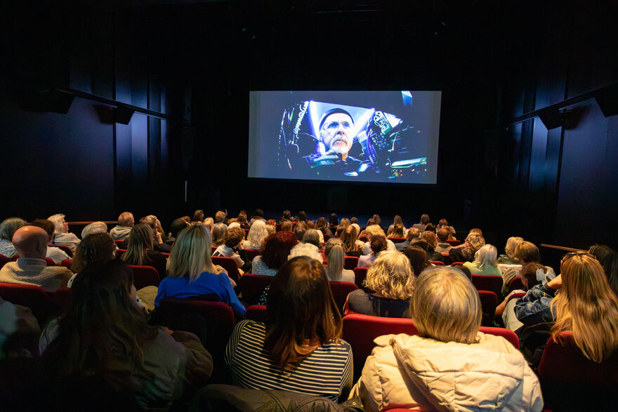 View from behind of an audience in a darkened cinema screen