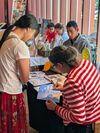 A woman signs a copy of her book for a customer at a Book Fair