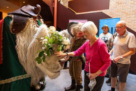 A large lion puppet being stroked by a visually impaired woman in a pink topr