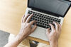 A close-up of a person's hands typing on a laptop