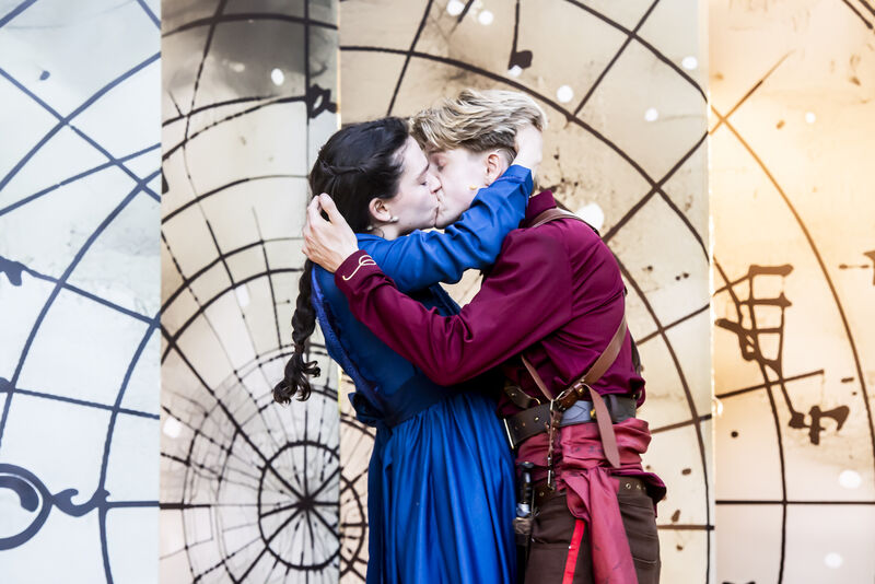 Two actors kiss and embrace 